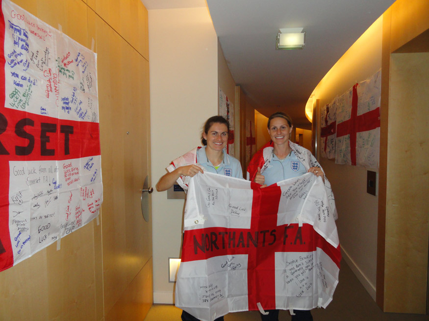 Karen Carney (left) and Kelly Smith wrap themselves in a 'good luck' flag sent to Germany by the Northants FA.